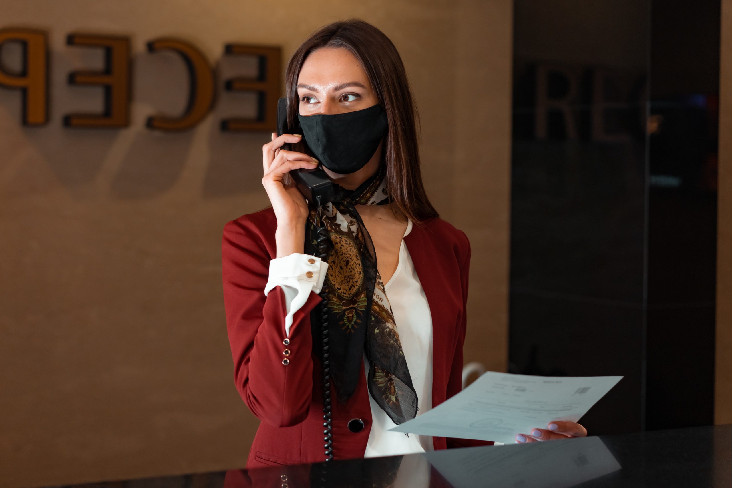 masked female receptionist taking a phone call
